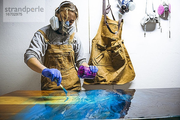 Kunstharzkünstlerin beim Mischen von Kunstharzfarbe mit einfachen Werkzeugen