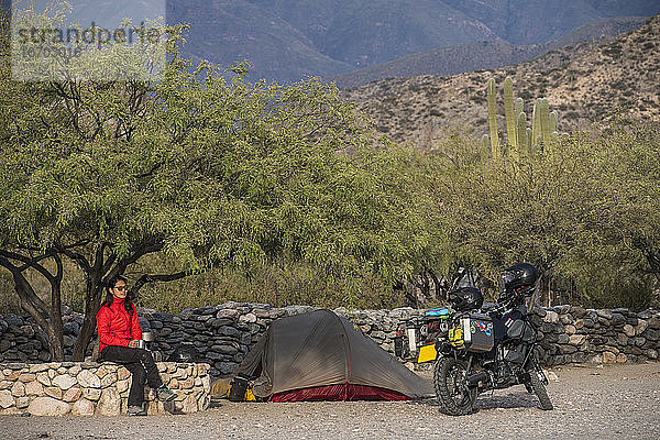 Frau sitzt neben dem Motorradlager in den Ruinas de Quilmes