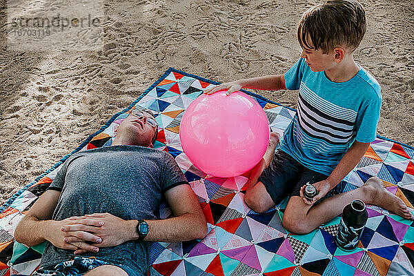 Vater und Sohn entspannen sich auf einer Picknickdecke an einem sonnigen Tag