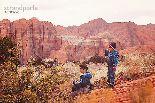 Zwei Jungen spielen auf einem Wanderweg in der Nähe der roten Sandsteinfelsen und Berge