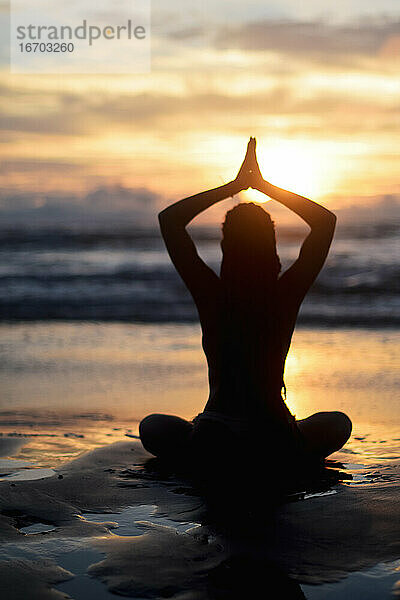 Silhouette einer Frau beim Yoga bei Sonnenuntergang