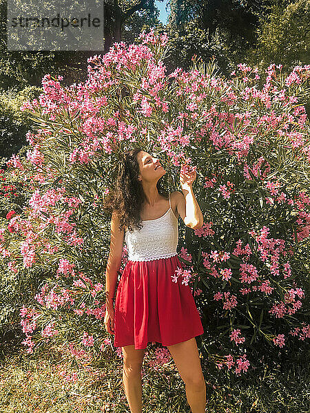 Mädchen im roten Kleid riecht an rosa Blumen