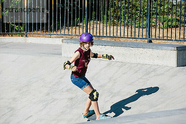 Teenager-Mädchen konzentriert sich beim Skateboardfahren im Skatepark