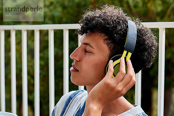 Junger Mann mit Afro-Haar schließt die Augen beim Hören von Musik