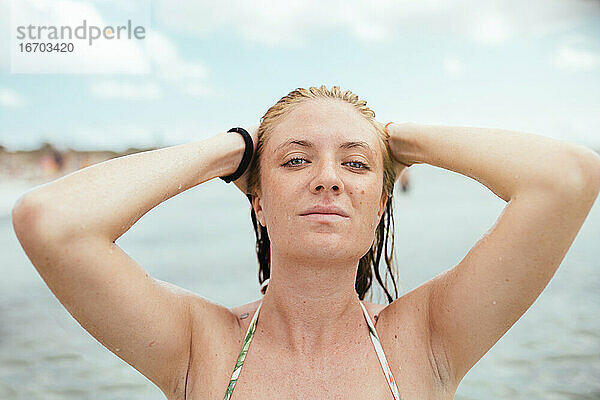 Junge blonde Frau  die ihr nasses Haar im Mittelmeer berührt