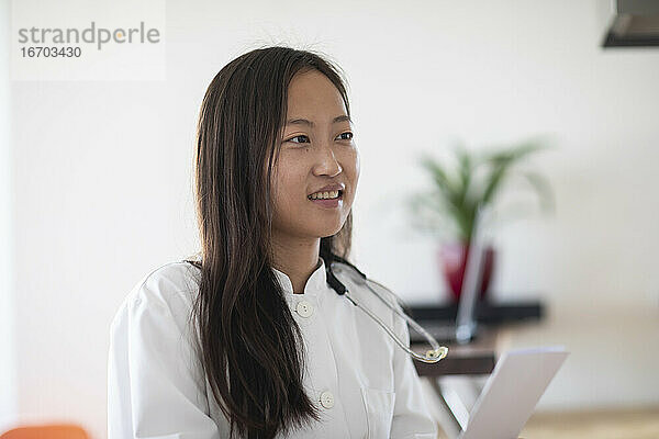 junge asiatische Ärztin mit Bericht in einer Praxis