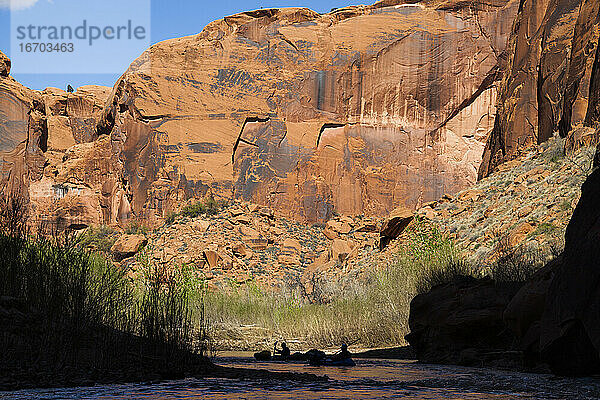 Menschen paddeln auf Packrafts unterhalb hoher Klippen auf dem Escalante River  Utah