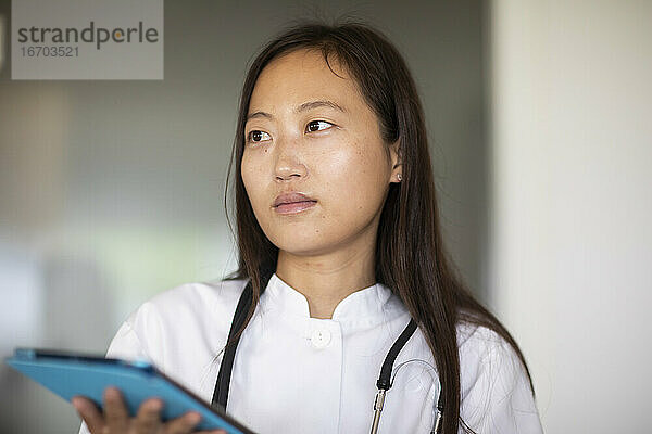 junge Asiatin Ärztin Frau mit Bericht in einer Praxis