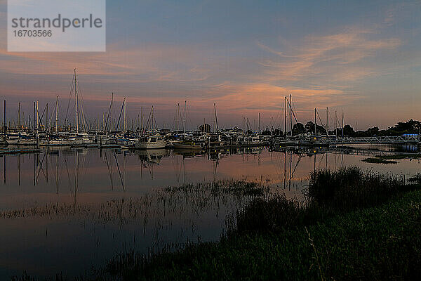 Boote im Hafen bei Sonnenuntergang mit bunten Himmel spiegelt sich im Wasser