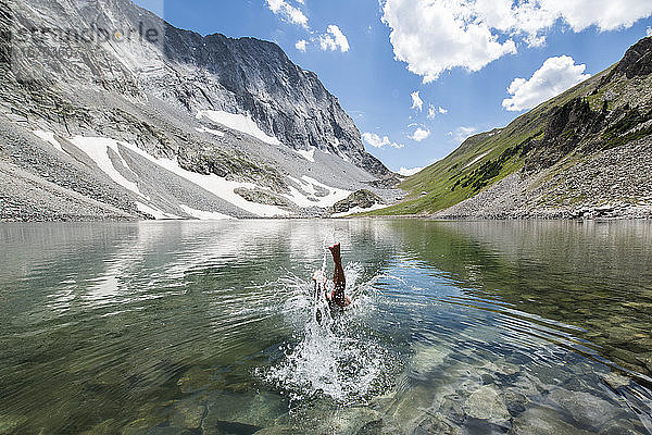 Frau taucht im See inmitten der Berge