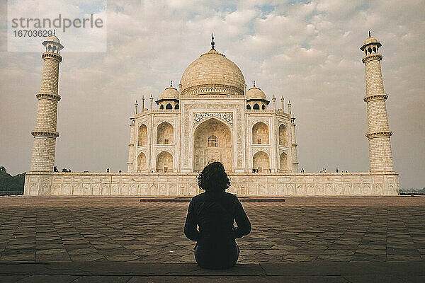 Junge Frau bewundert die Schönheit des Taj Mahal bei Sonnenaufgang an einem bewölkten Tag  Agra  Indien