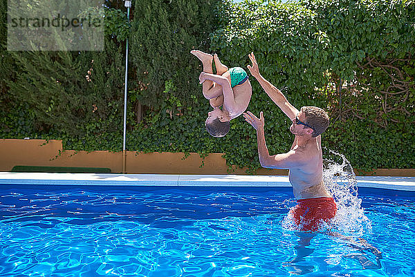 Sommerferien. Vater und Sohn spielen in einem Pool.