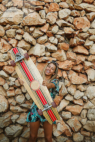 Junge glückliche Frau mit Skateboard und Sonnenbrille