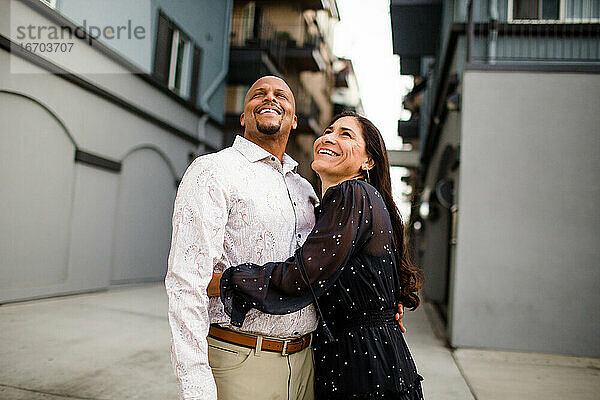 Spätes vierzigjähriges Paar  das lachend in einer Gasse in San Diego steht