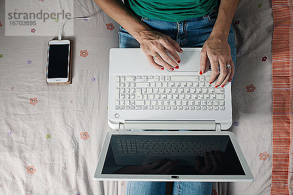 Frau arbeitet mit Laptop auf dem Bett