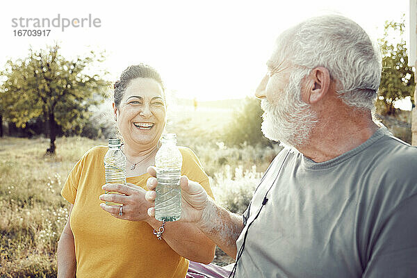 Ein älteres Paar lacht  während es sich ausruht  um Wasser zu trinken