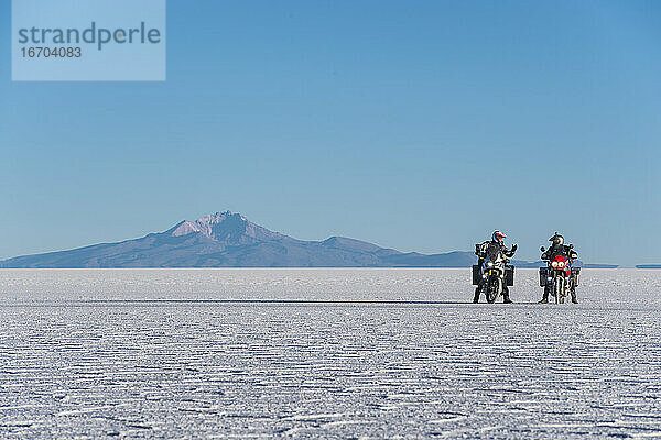 Zwei Männer fahren mit dem Motorrad über die Salinen von Uyuni