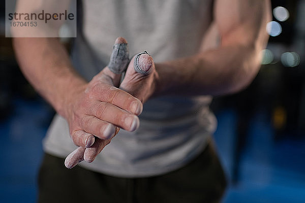 Geschnittener Sportler  der Magnesium auf die Hände verteilt