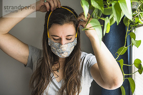 Frau zu Hause mit selbstgebauter Gesichtsmaske Schutz PSA