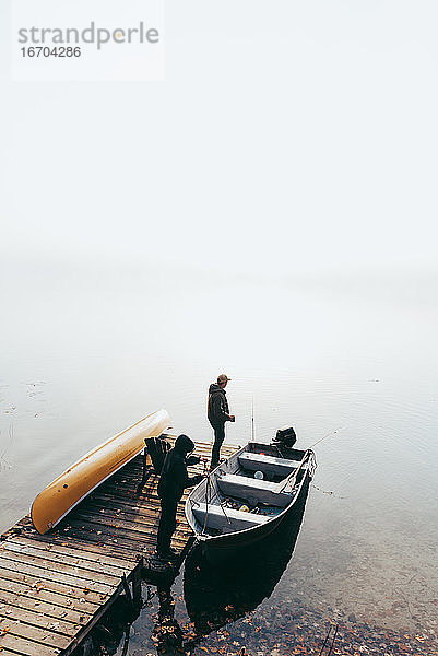 Mann und Kind machen sich an einem nebligen Tag in einem Boot zum Fischen bereit.