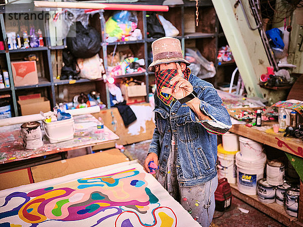Eine Künstlerin mit verdecktem Gesicht arbeitet in ihrem Atelier.