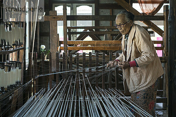 Ältere birmanische Frau bereitet Fäden für die Arbeit am Webstuhl vor  Inle-See  Myanmar