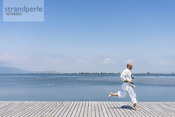 Ein Mann übt Kampfsportarten auf einem Holzsteg am Meer