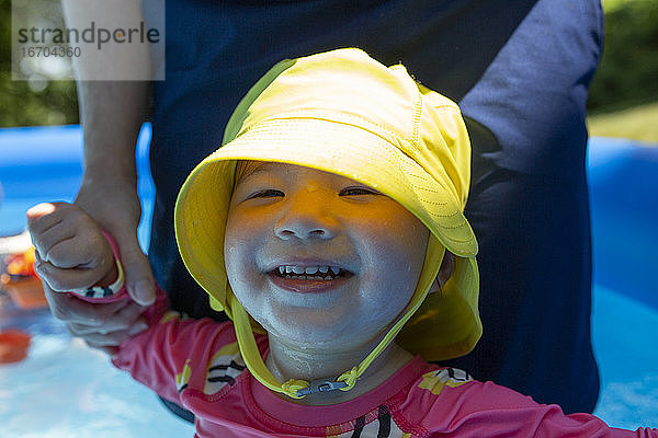 Kleinkind Mädchen in Kiddie Swimming Pool lächelt mit Mama hält sie