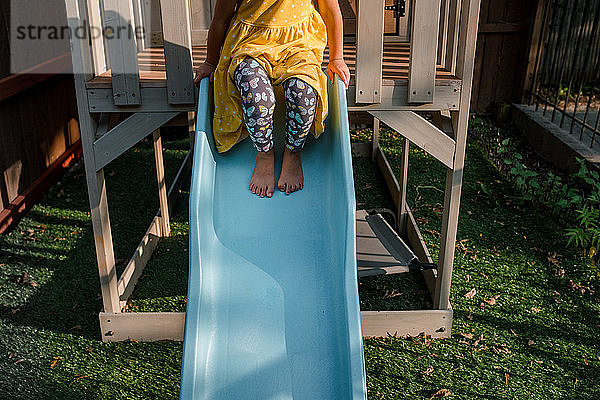 Kind auf der Spitze einer blauen Rutsche sitzend