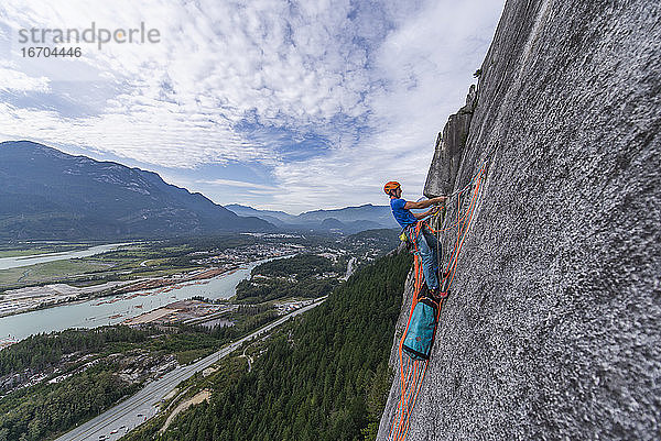 Mann schleppt Schleppsack beim Klettern auf Granit mit Blick auf Squamish