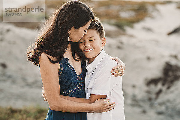 Liebevolle Mutter umarmt lächelnden Teenager-Sohn