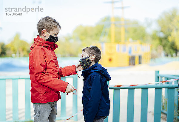 Kleiner Junge setzt seinem Bruder die Maske auf