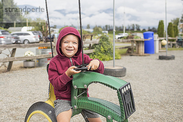 Junge sitzt auf einem Traktor auf dem Bauernhof  der aus recycelten Reifen hergestellt wurde