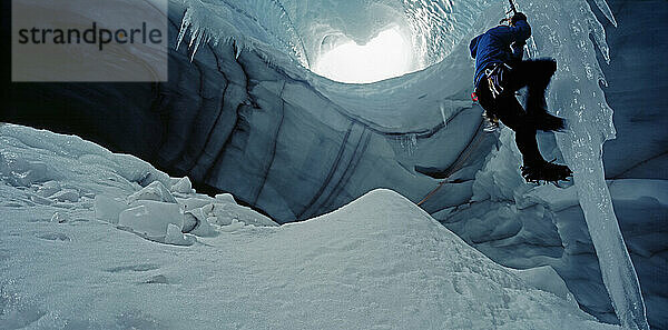 Eiskletterer erklimmt Eiszapfen in einer Höhle unter dem Langjokull-Gletscher