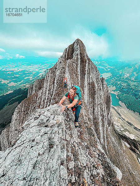 Zwei Bergsteigerinnen auf einem schmalen Grat über einem Alpensee in den Schweizer Alpen