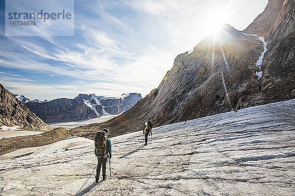 Rucksacktouristen überqueren einen vergletscherten Berg auf Baffin Island.