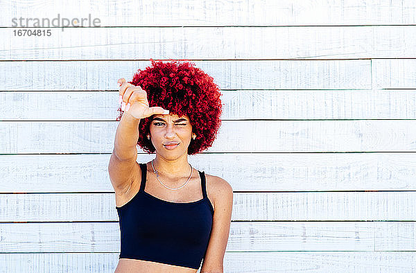 Porträt einer Frau mit rotem Afro-Haar auf weißem Hintergrund.