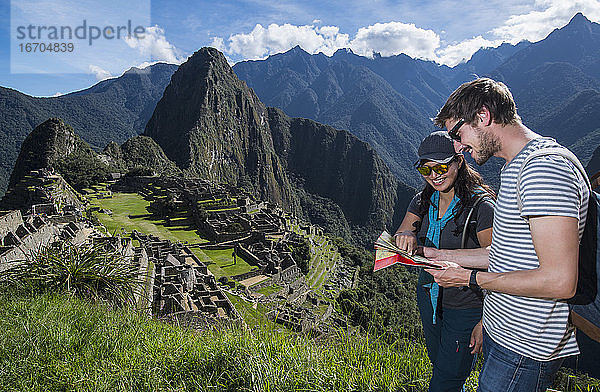 Paar bei den Inka-Ruinen mit Blick auf eine Faltkarte  Machu Picchu  Peru