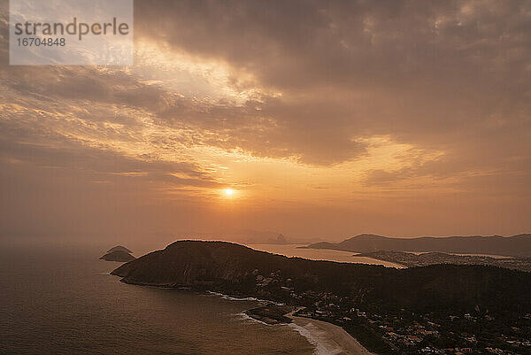 Schöner Blick auf den Sonnenuntergang von der Hügelspitze auf das Meer  den Strand und die orangefarbenen Wolken