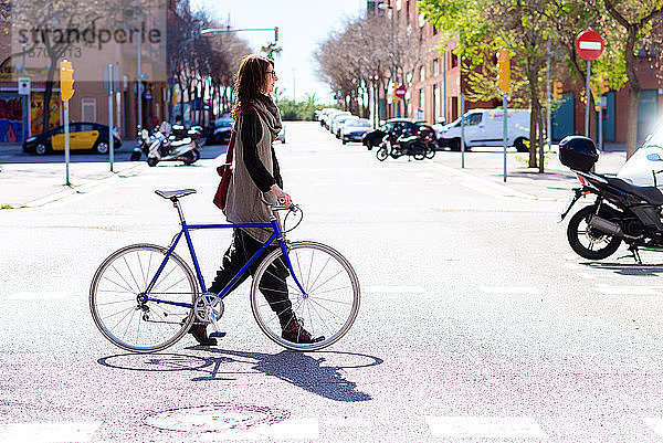 Junge lächelnde Frau auf einer Straße mit Fahrrad