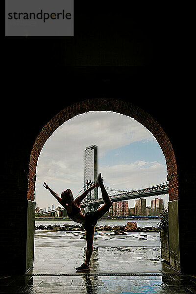 Silhouette einer Frau  die sich vor der Skyline streckt.