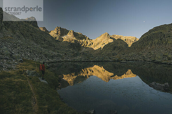 Ein junger Mann mit Rucksack betrachtet die Spiegelung im See  Sierra de Gredos