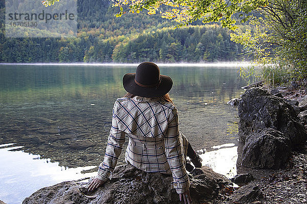 Eine Person sitzt und entspannt an einem Alpensee