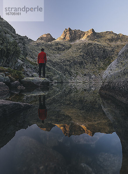 Ein junger Mann steht bei Sonnenaufgang auf einem Felsen in der Sierra de Gredos  Spanien