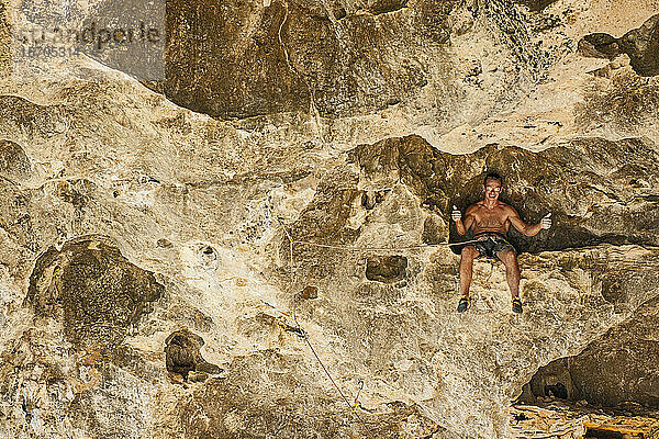 Mann ruht sich beim Klettern in Yangshuo / China auf einem Felsvorsprung aus