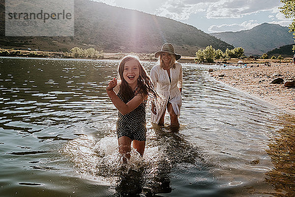 Lächelndes junges Mädchen  das an einem sonnigen Nachmittag durchs Wasser läuft
