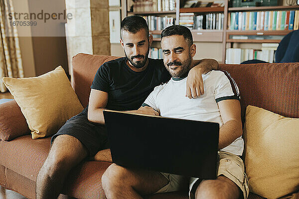 schwules Paar sitzt auf der Couch und schaut auf den Laptop