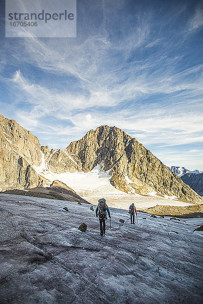 Zwei Männer überqueren einen Gletscher über einen hohen Bergpass.