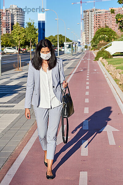 Frau geht mit einer Maske die Straße entlang.