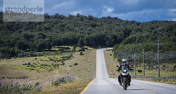 Frau fährt mit ihrem Motorrad auf einer einsamen Straße in Patagonien  Chile